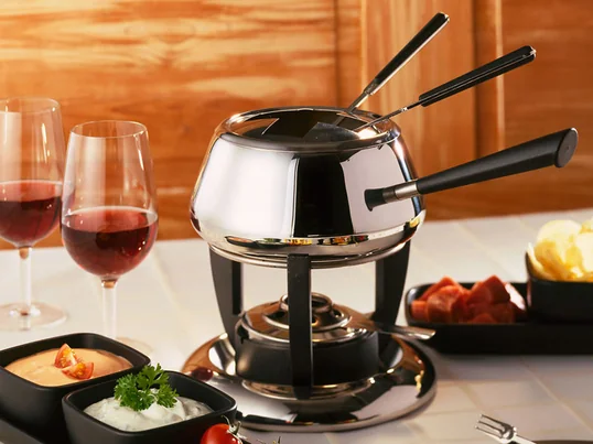 Die Fondue-Garnitur Classic des schweizer Unternehmens Spring erscheint in der traditionellen, etwas bauchigen Form mit langem Stiel auf einem formschönen Rechaud.