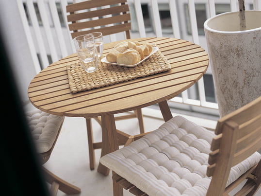 Gartenmöbel aus Holz verleihen dem Balkon einen rustikalen Look. Am Vendia Tisch mit Stühlen von Skagerak lässt es sich wunderbar unter freiem Himmel frühstücken.