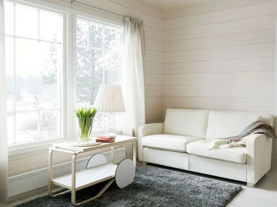 Der Servierwagen 901 von Artek ist der Hingucker in Ihrem Wohnzimmer und noch dazu ein praktischer Beistelltisch. Besonders schön wirkt er im Tageslicht, das durch das Fenster scheint.