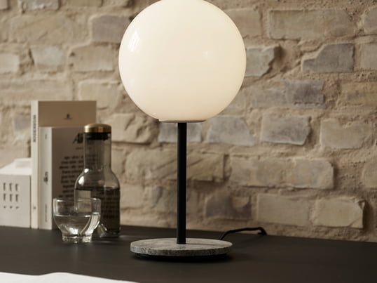 Die TR Tischleuchte von Menu aus Marmor in grau mit einem Leuchtmittel aus Glas in shiny opal macht sich toll als Arbeitsleuchte auf jedem Schreibtisch.