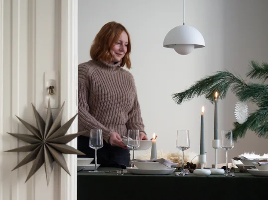 Die Nappula Kerzenständer von Iittala in der Ambienteansicht: Die weißen Kerzenständer und die Essence Trinkgläser kommen auf der grünen Tischdecke hervorragend zur Geltung.