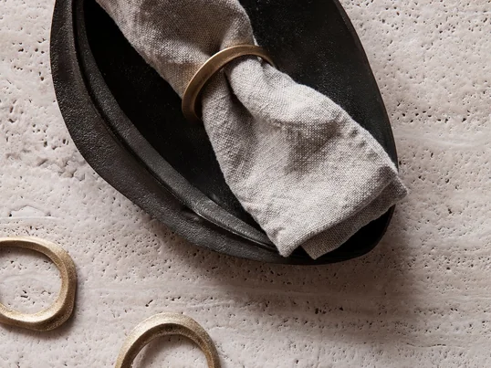 Die dekorativen Flow Serviettenringe aus Messing im praktischen 4er-Set und das Forest Dekotablett aus Messing in schwarz von Ferm Living in der Ambienteansicht.