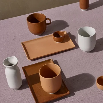 Das Eli Geschirr von Broste Copenhagen in caramel und soft light grey matt auf einer fliederfarbenen Tischdecke