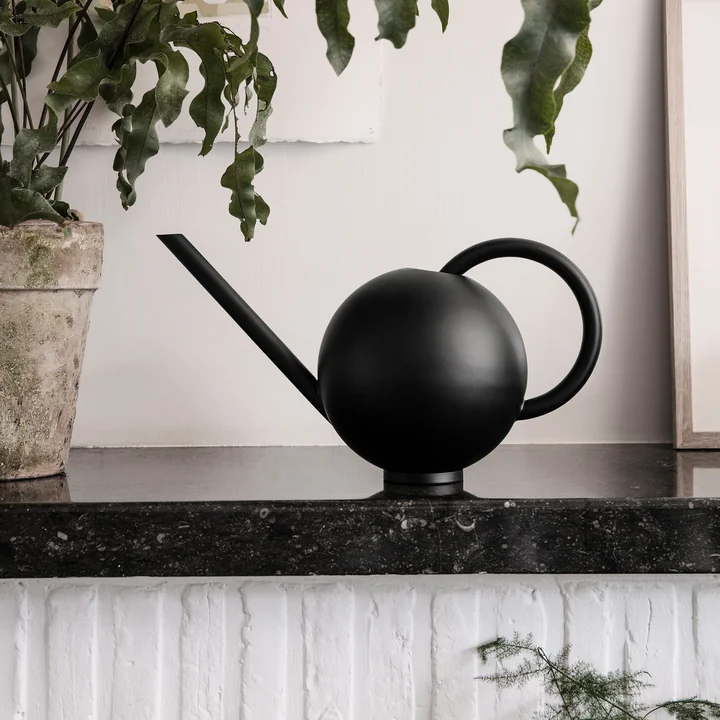 Orb Gießkanne von Ferm Living neben einer Pflanze