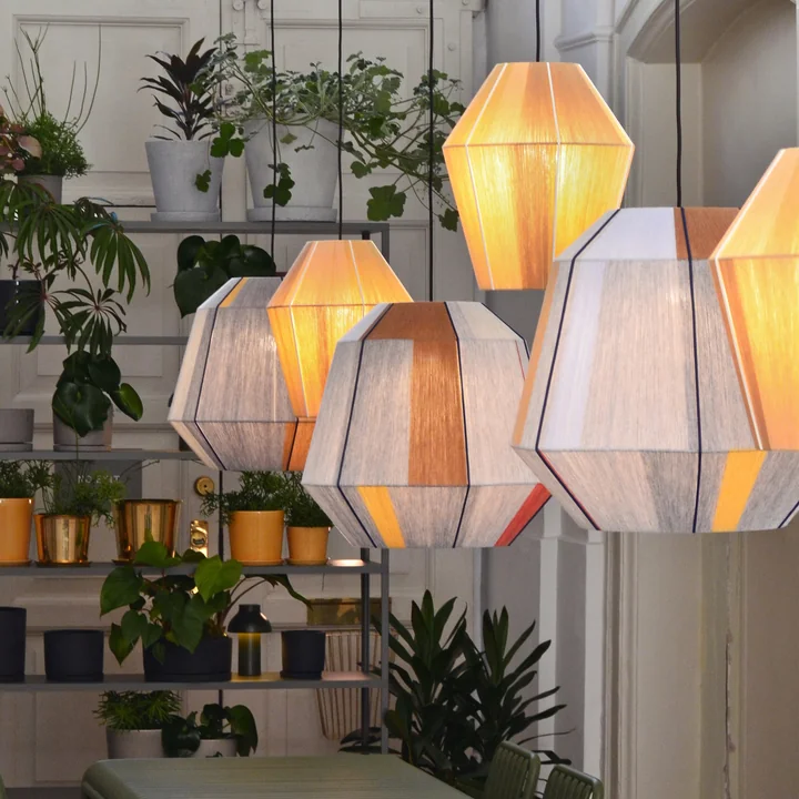 Die Bonbon Lampenschirme von HAY im leuchtenden Zustand in einem Zimmer mit viel Pflanzen