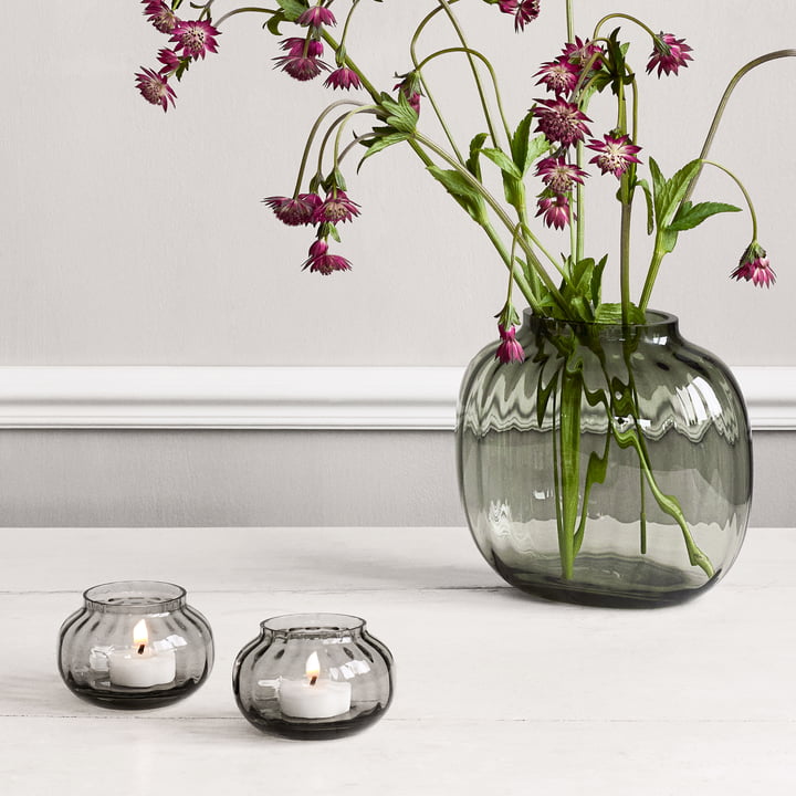 Die Primula Teelichthalter, Ø 9,5 cm, smoke neben der dunklen Primula Vase von Holmegaard