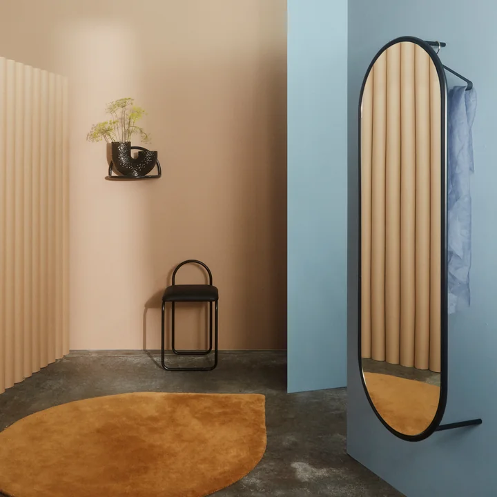 Der Angui Wandspiegel von AYTM an einer blauen Wand in der Garderobe