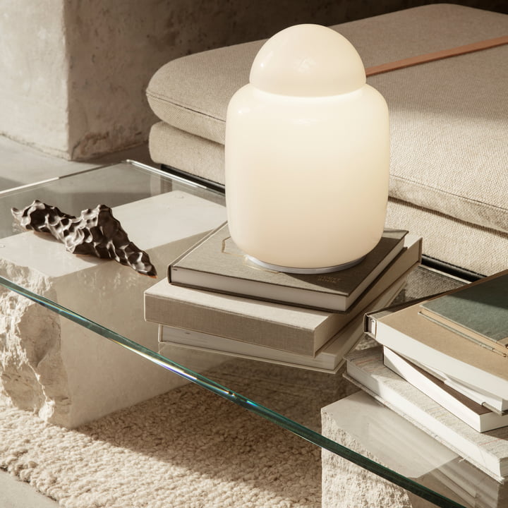 Die Bell Tischleuchte von Ferm Living auf Bücherstapeln auf einem Glas-Couchtisch