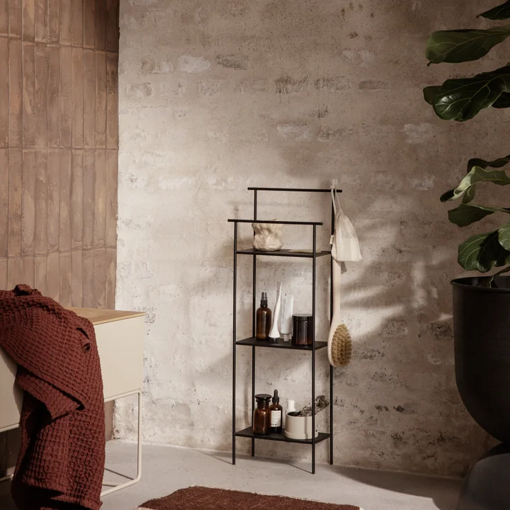 Das Dora Badezimmerregal von Ferm Living mit Bad-Accessoires neben einer großen Zimmerpflanze
