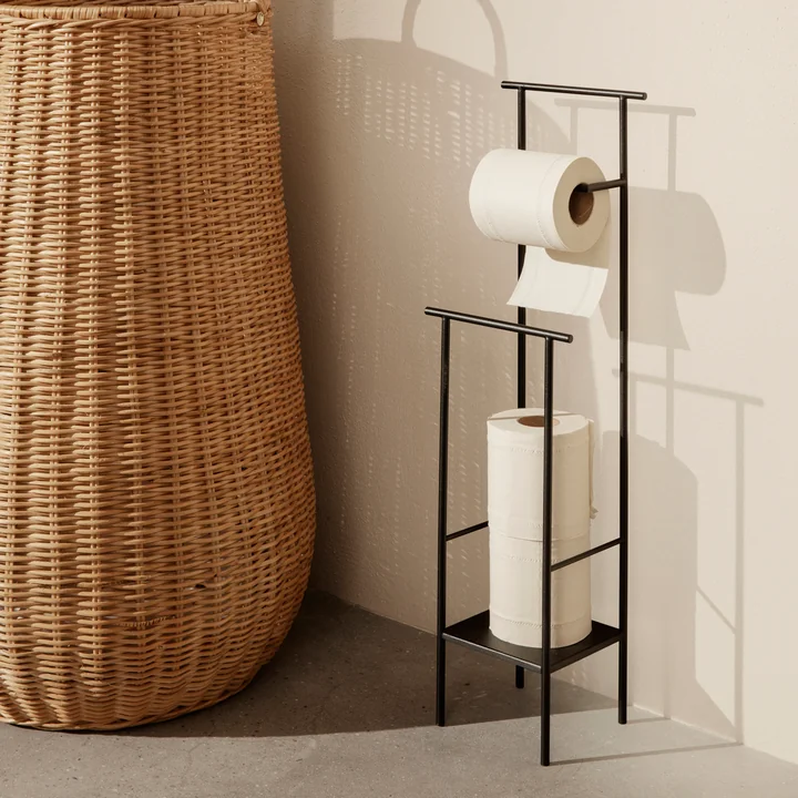 Der Dora Toilettenpapierhalter von Ferm Living neben einem großen Rattan-Korb