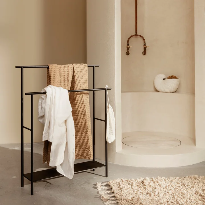 Der Dora Handtuchhalter von Ferm Living mit Handtüchern neben der Stein-Dusche