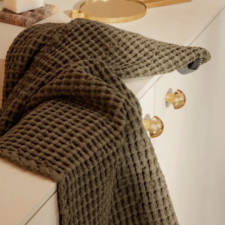 Das Organic Badetuch von Ferm Living in olive auf dem Waschbecken-Schrank im Bad