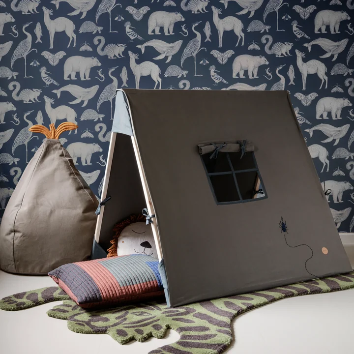 Das Spielzelt von Ferm Living in olive auf einem Tiger-Teppich vor einer blauen Tapete
