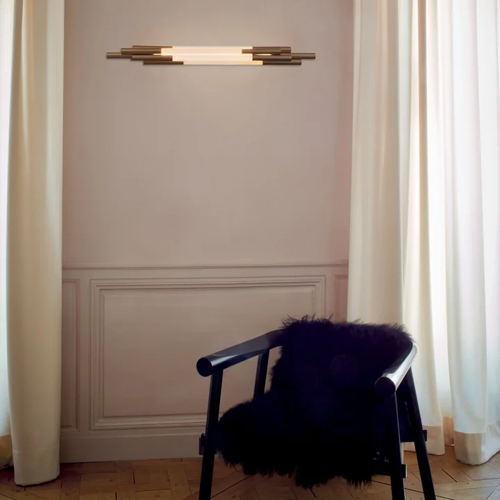 Die Org LED Wandleuchte von DCW an der Wohnzimmer-Wand über einem Armlehnstuhl