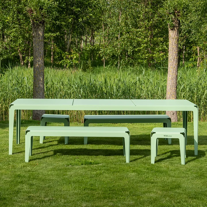 Die Bended Bench Bank und der Bended Tisch von Weltevree auf einer grünen Wiese