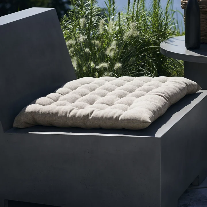 Das Fine Outdoorkissen von House Doctor auf einem Beton-Loungesessel