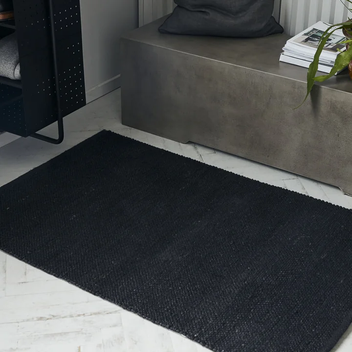 Der schwarze Hempi Teppich-Läufer von House Doctor vor einer Beton-Sitzbank