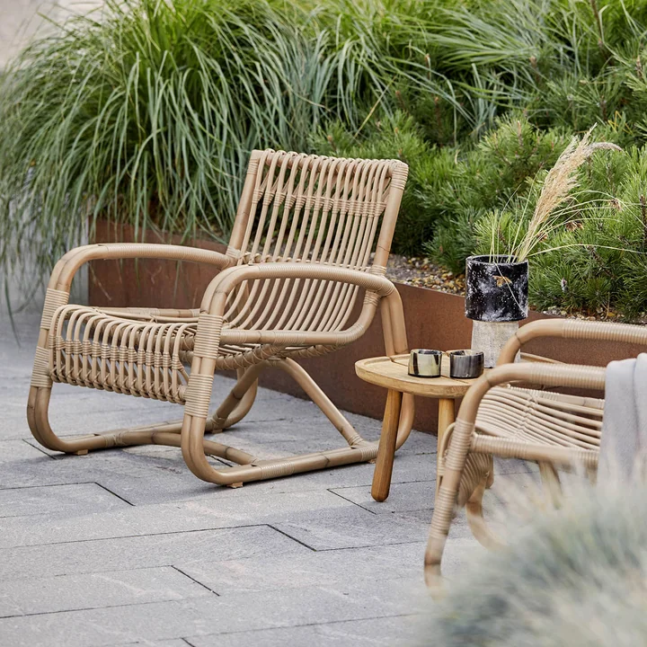 Der Curve Loungesessel Outdoor von Cane-line auf der grün bepflanzten Terrasse
