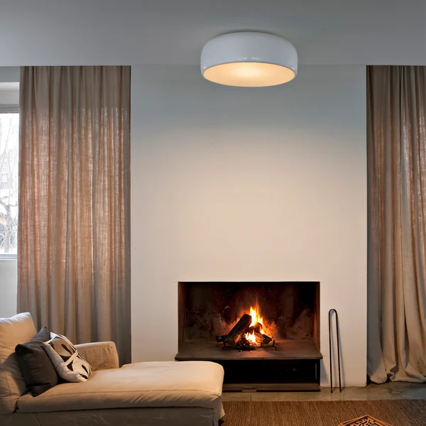Die Smithfield Pro Deckenleuchte von Flos im Wohnzimmer über einer beigen Couch mit Kamin